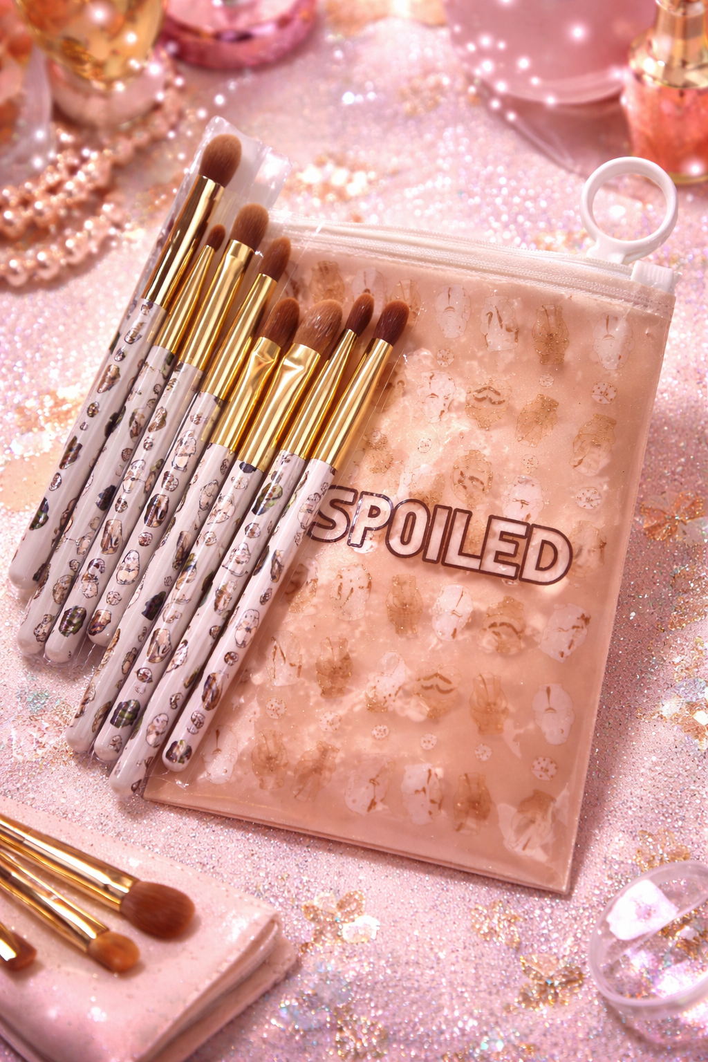 Set of makeup brushes with a 'SPOILED' pouch on a glittery surface