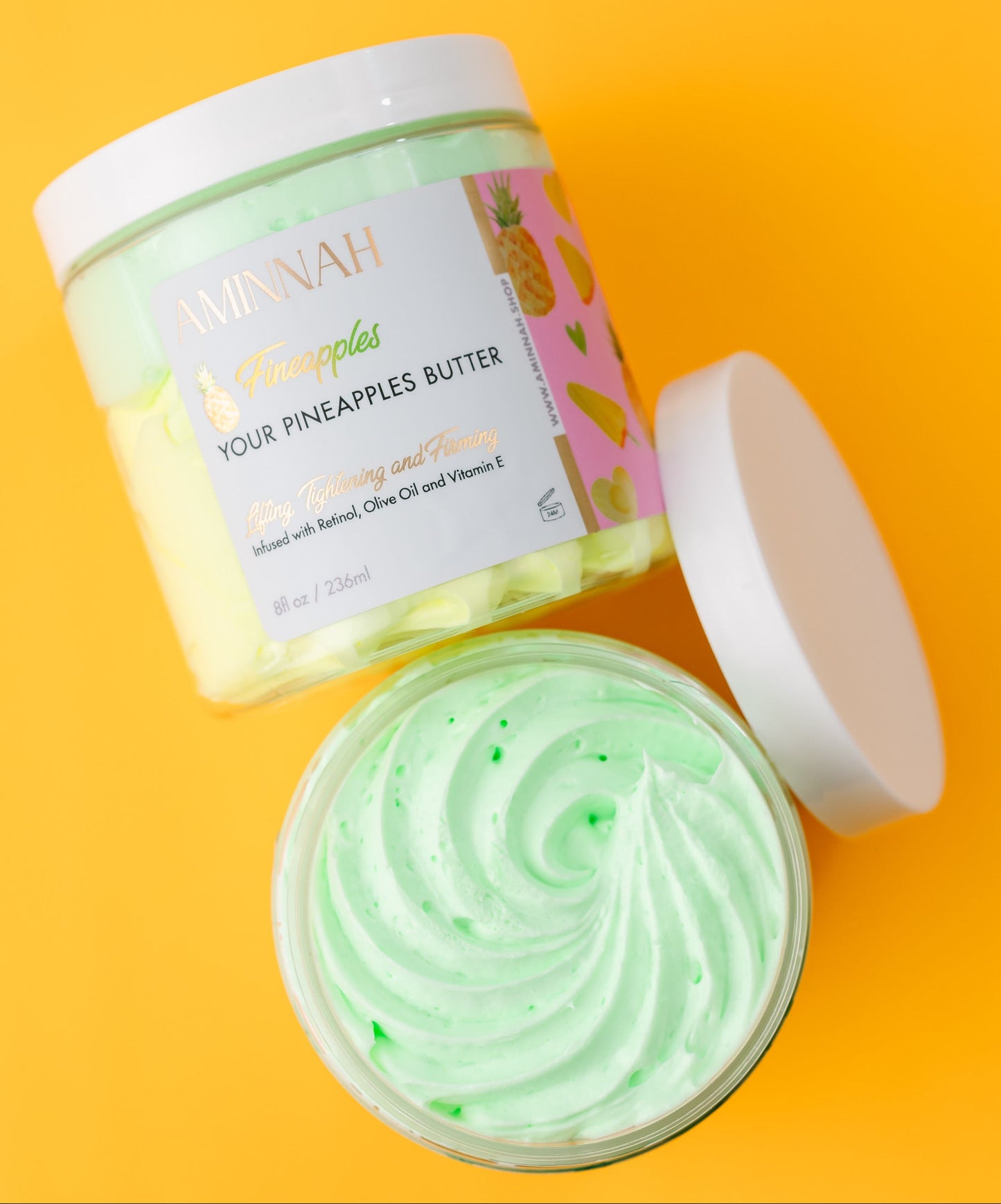 Jar of vegan whipped body butter with a pink, white and gold label on an orange background. Organic, Cruelty-Free, Natural Ingredients by a Woman Owned Brand. AMINNAH SKINCARE