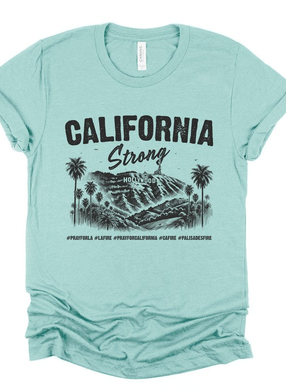Mint green unisex short-sleeve T-shirt featuring a black "California Strong" Hollywood graphic with palm trees and mountain landscape, symbolizing Los Angeles pride and wildfire community support.