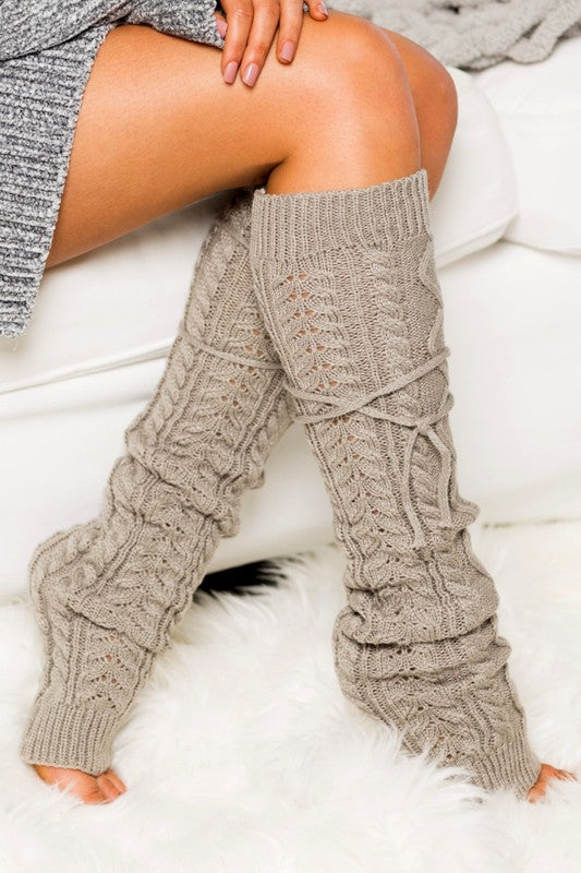 Knitted leg warmers worn by a person on a white surface