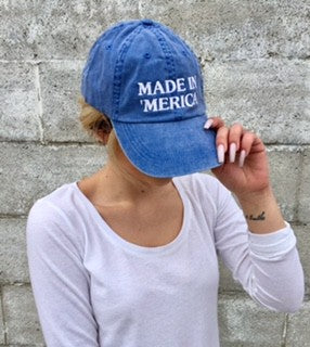 Made in Merica VintageWashed Baseball Cap in the color blue. Woman wearing blue baseball cap against a stone background