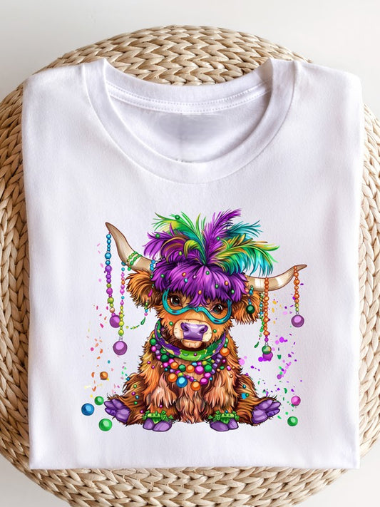 White unisex crewneck T-shirt featuring a colorful Highland cow wearing a purple feather headdress, Mardi Gras beads, and a festive mask in green, gold, and purple on a clean white background. Fun Mardi Gras carnival graphic tee with whimsical farm animal design.