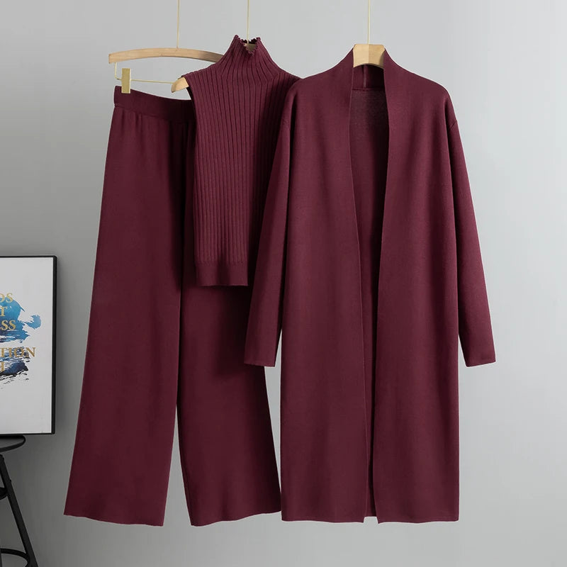 Maroon outfit with coat, pants, and sweater on hangers against a gray background