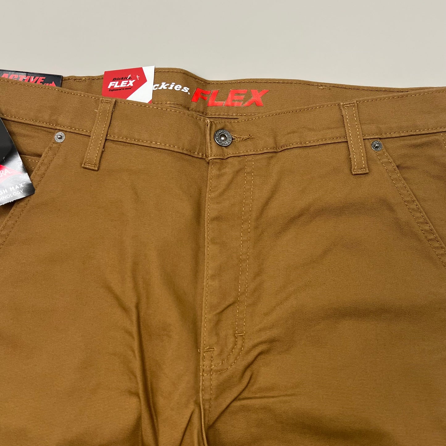 Brown pants with Flex and Dickies branding on a beige background