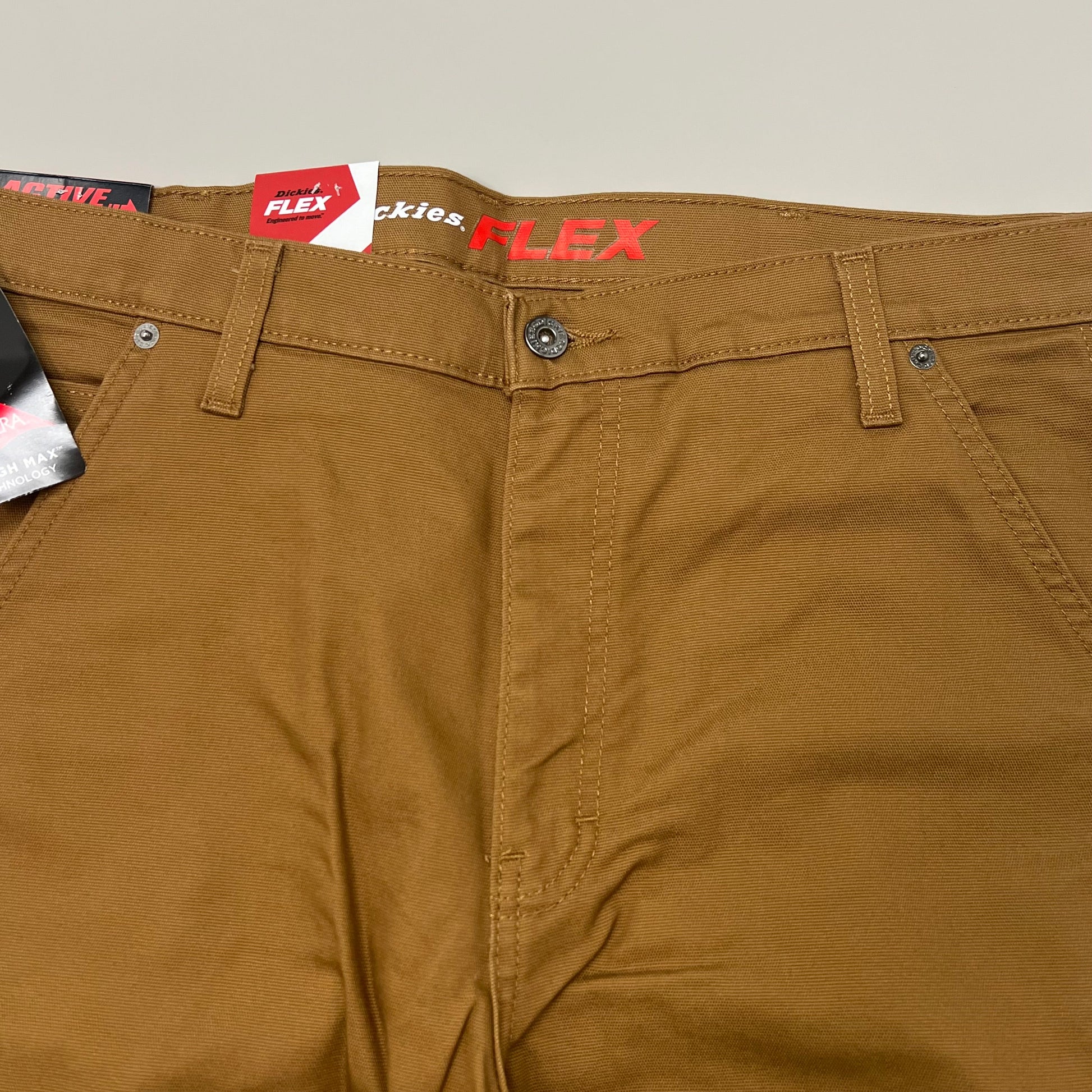 Brown pants with Flex and Dickies branding on a beige background