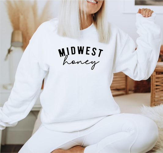 Person wearing a white sweatshirt with 'Midwest honey' text in a casual setting.