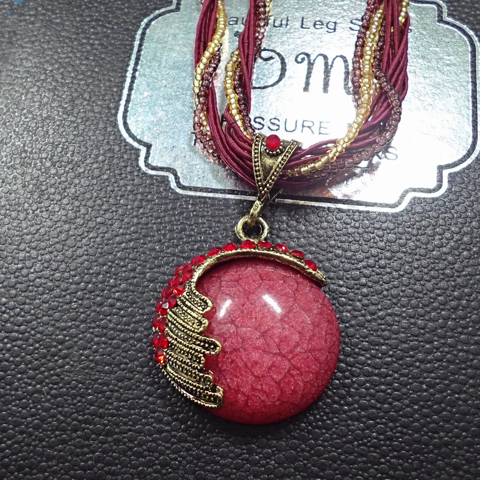 Necklace with a pink pendant and gold accents on a textured surface