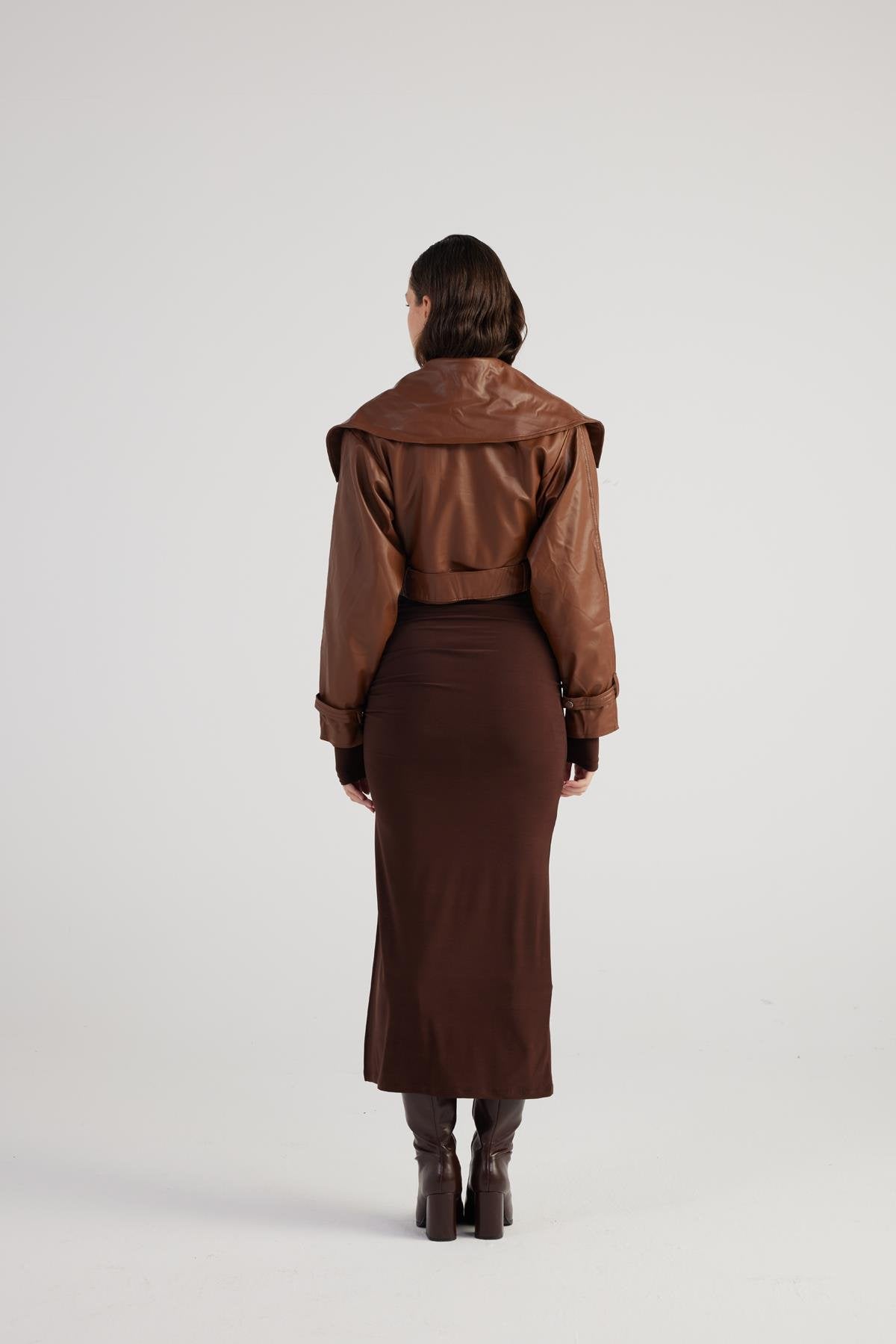 Person wearing a brown coat and skirt set on a white background
