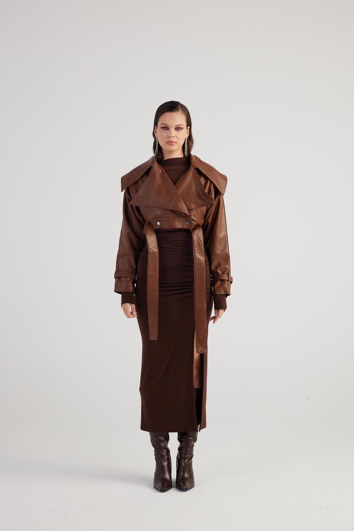 Person wearing a brown coat and skirt set on a white background