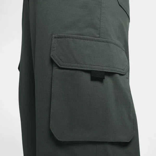 Close-up of a dark olive green utility jacket showing a large flap cargo pocket with a black hook-and-loop strap closure. These lightweight, sweat-wicking pants are made for movement and comfort. With 6 pockets