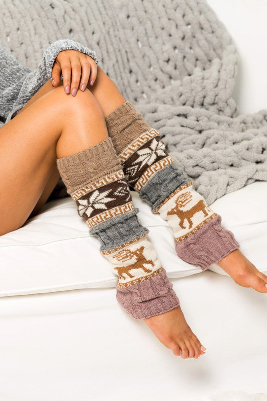 Leg warmers with a pattern of animals worn by a person sitting on a white surface with a gray textured blanket.