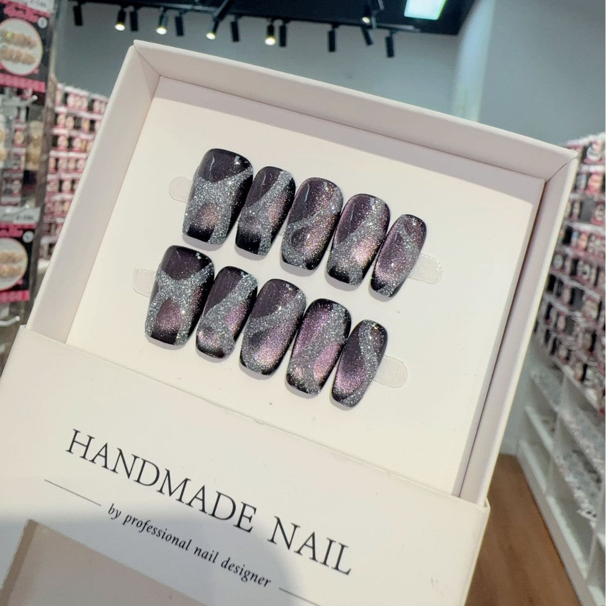 Box of handmade press-on glitter nail art with high gloss gel glittery design in a store setting