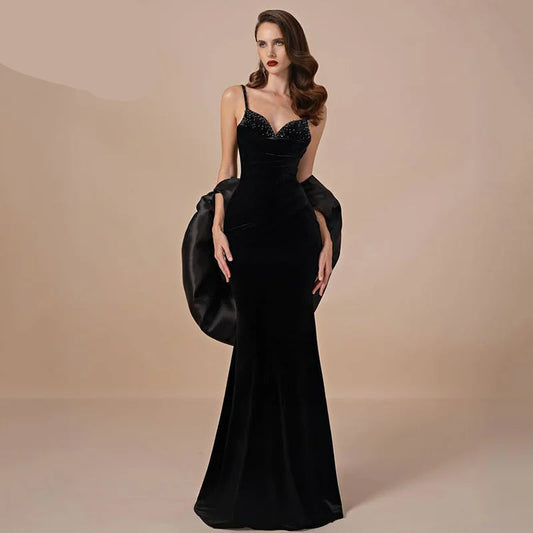 Woman wearing a black evening gown with a large clutch against a beige background, featuring the brand 'OEING'. OEING Elegant Mermaid Prom Dress Black Sleeveless Floor Length Velvet Beading Evening Dresses robes de soirée Customized