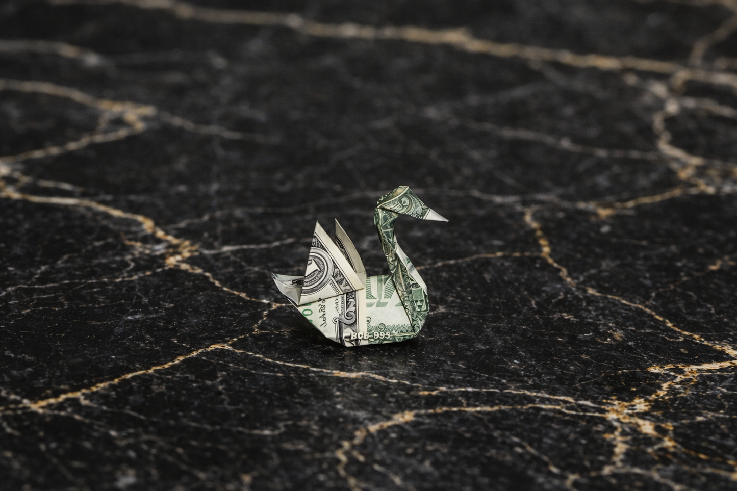 Origami swan made from a dollar bill on a textured black surface