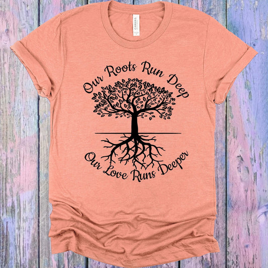 Peach t-shirt with a black tree graphic and text on a wooden surface