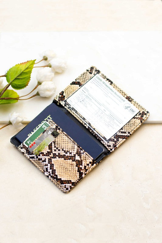Snakeskin print passport and vaccine card holder wallet with RFID blocking design, featuring card slots, passport pocket, and CDC vaccination card holder on a light neutral background.