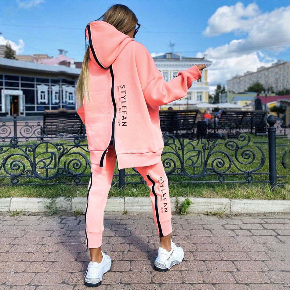 Person wearing a pink zip up STYLEFAN tracksuit with 'STYLEFAN' branding outdoors.