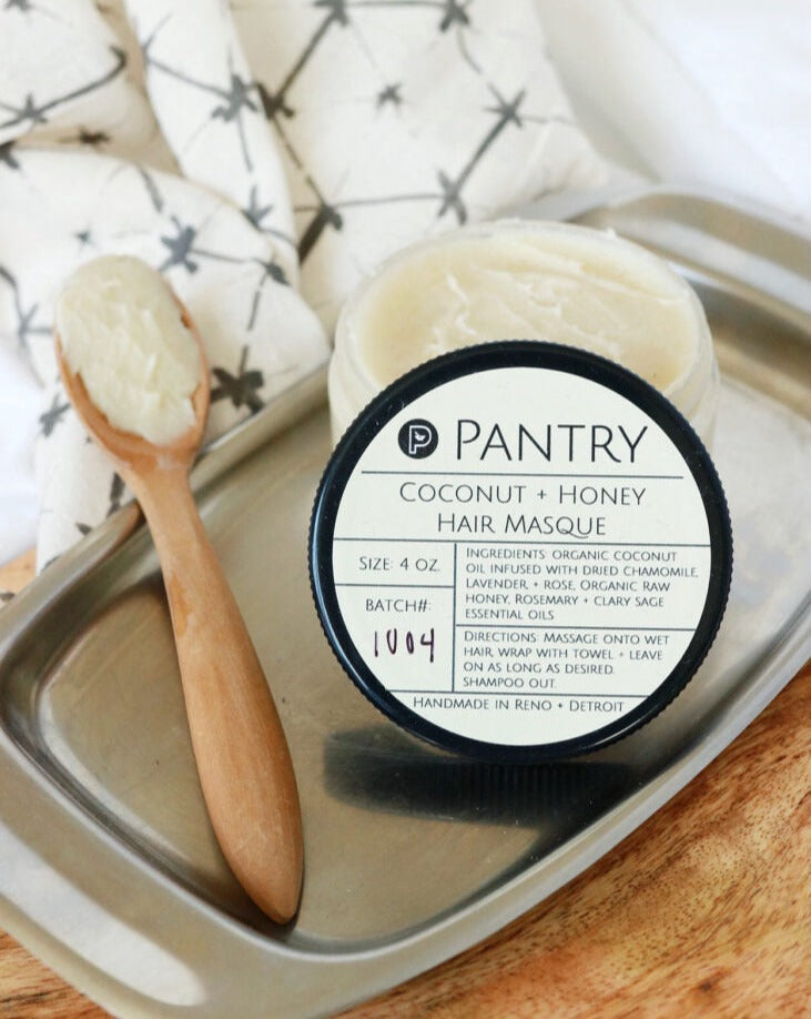 Coconut and honey hair masque with a wooden spoon on a metal tray, against a neutral background. Coconut + Honey Hair Masque | Leave-In Hair Masque