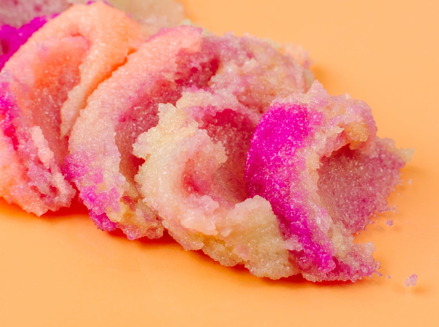 Pink and white ice cream scoop shaped sugar body scrub on a yellow background. Fruit scent