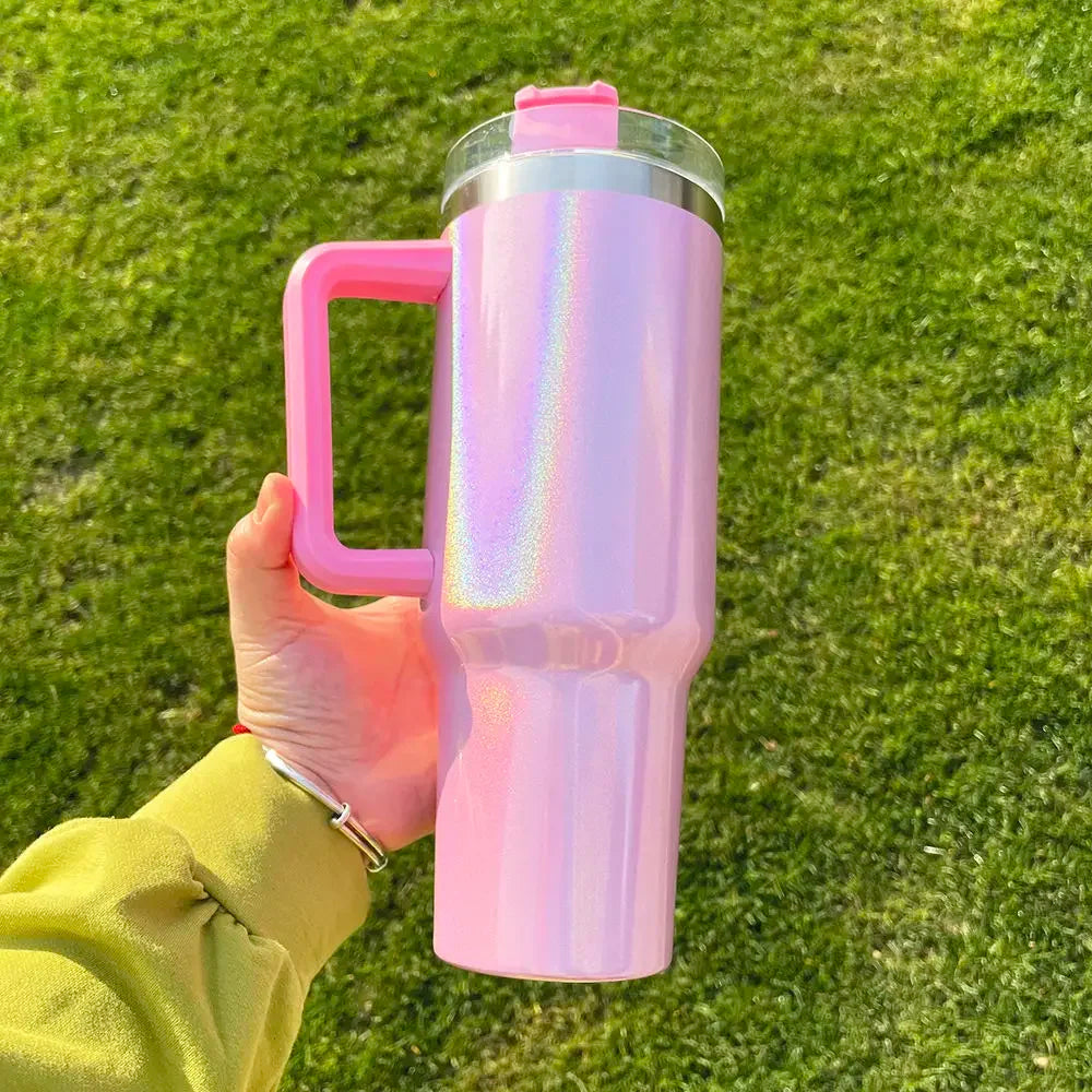 Pink iridescent tumbler with a handle held by a person against a grass background