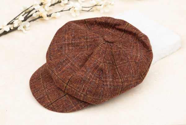 Brown plaid newsboy cap with a classic vintage design, structured crown, and short brim displayed on a light background.