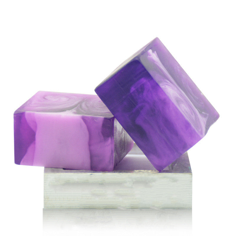 Purple and white marbled soap bars with a clear container on a white background