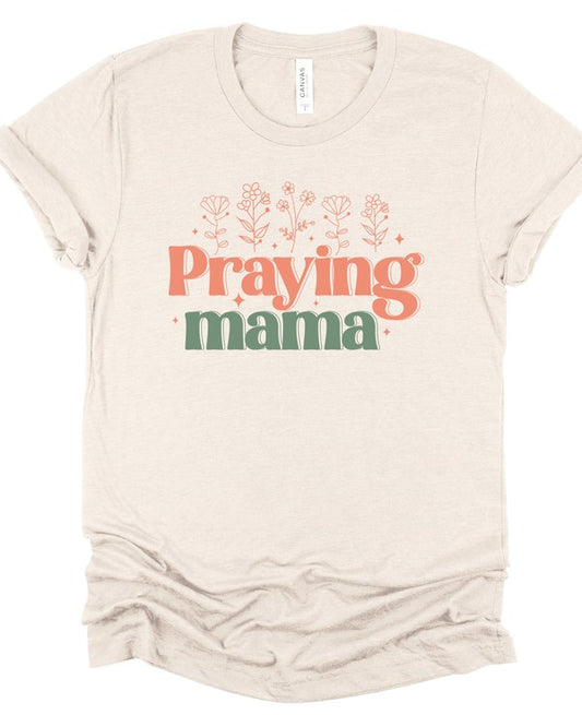 Beige t-shirt with 'Praying mama' text on a white background. Beige Bella + Canvas unisex t-shirt featuring a retro "Praying Mama" graphic in coral and sage green with delicate floral accents on a white background. Praying Mama Bella + Canvas Graphic T-Shirt – 100% Combed & Ring-Spun Cotton Christian Tee