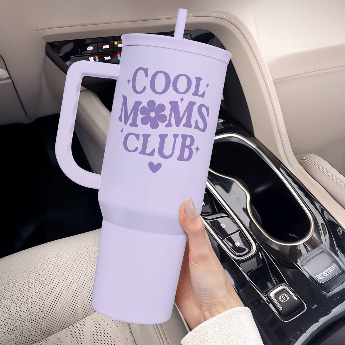 Purple tumbler with 'Cool Moms Club' text held in a car cup holder.