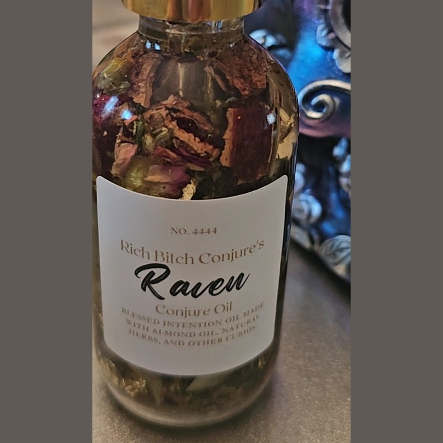 Bottle of 'Rich Bitch Conjure's Raven Conjure Oil' with a label on a surface. Raven Hoodoo Conjure Oil for Intuition, Manifestation, & Spiritual Power Ritual Oil