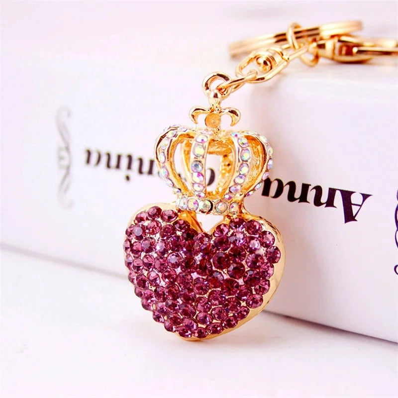 Pink rhinestone heart pendant keychain with a gold crystal crown and gold key ring on a white background, elegant women's bag charm and luxury car keychain accessory.