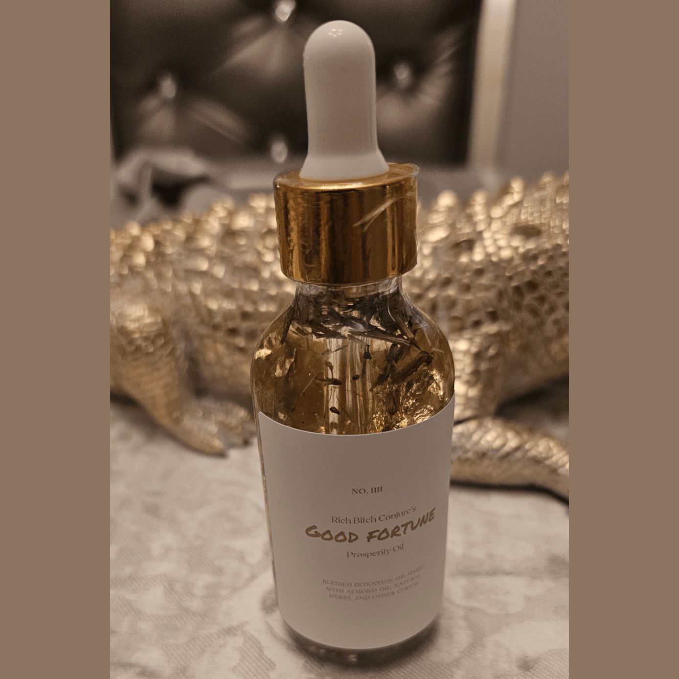 Bottle of 'Good Fortune' oil with dropper on a textured surface. Rich Bitch Conjure's Good Fortune Oil