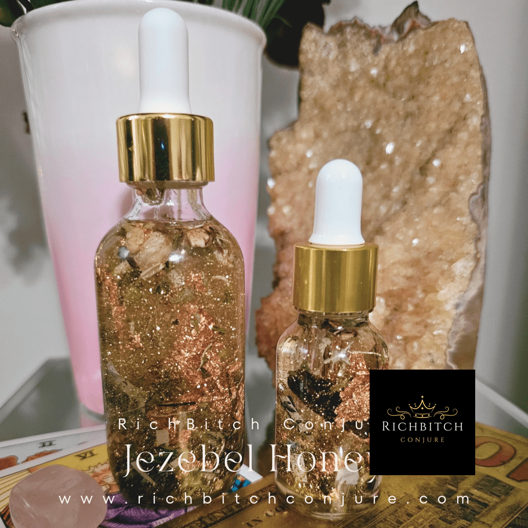 Rich Conjure's Jezebel Honey Oil. Two glittery dropper bottles with gold caps on a surface with crystals and a plant in the background.