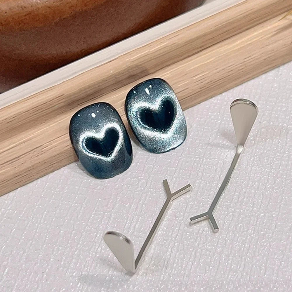 Professional product photography of a 2-piece love-shaped nail art magnet set featuring a heart-pattern design and Y-shape wire, displayed on a textured surface.