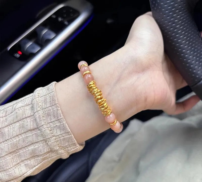 Hand wearing a gold bracelet with a car interior background