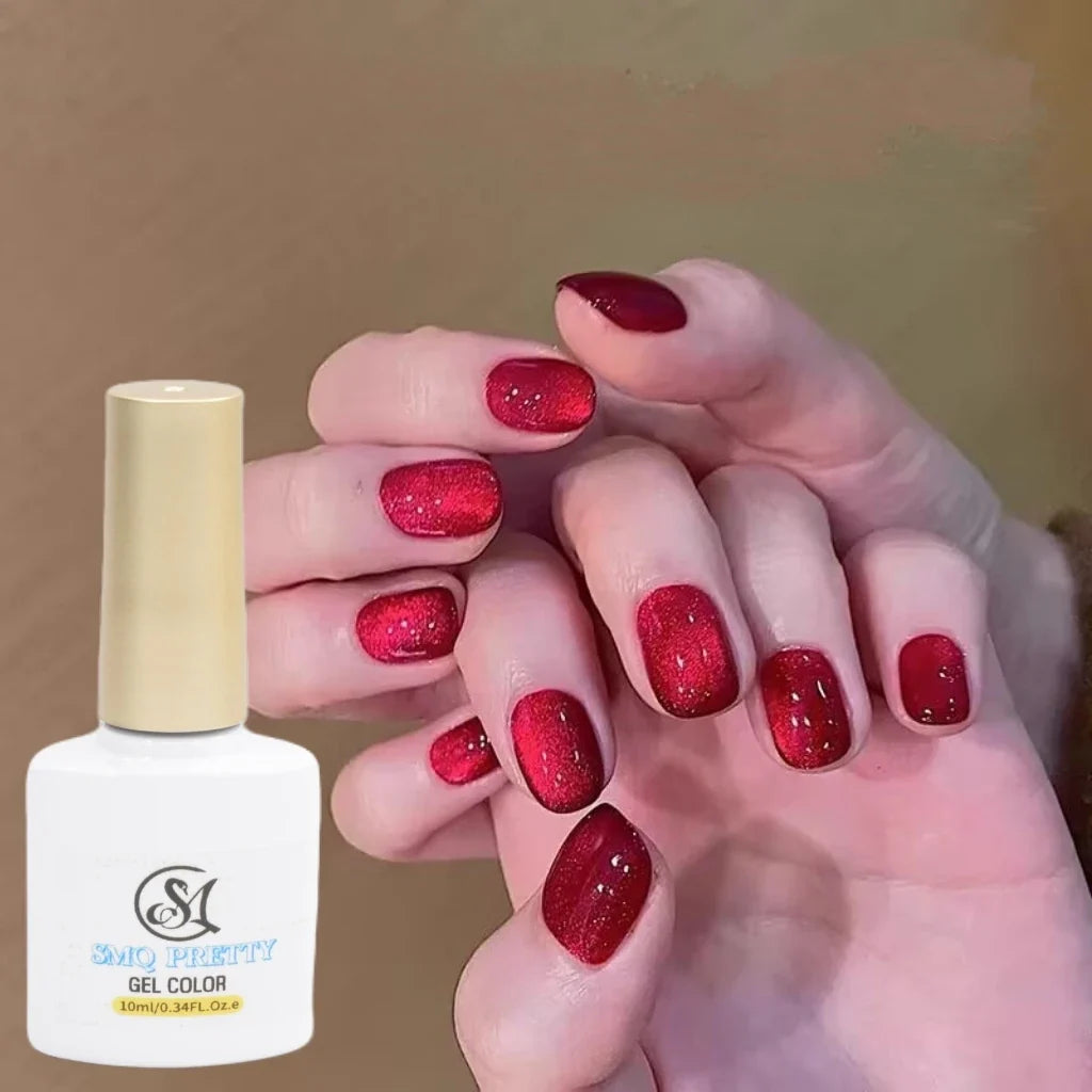 A close-up shot of a hand with vibrant red glittery nails holding a 10ml bottle of holographic cat-eye gel nail polish against a neutral background.