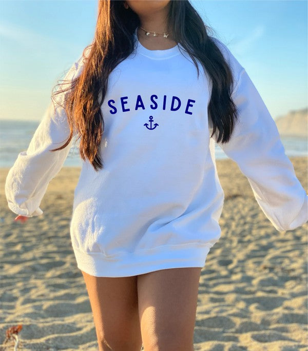 Person wearing a white sweatshirt with 'Seaside' text on a beach