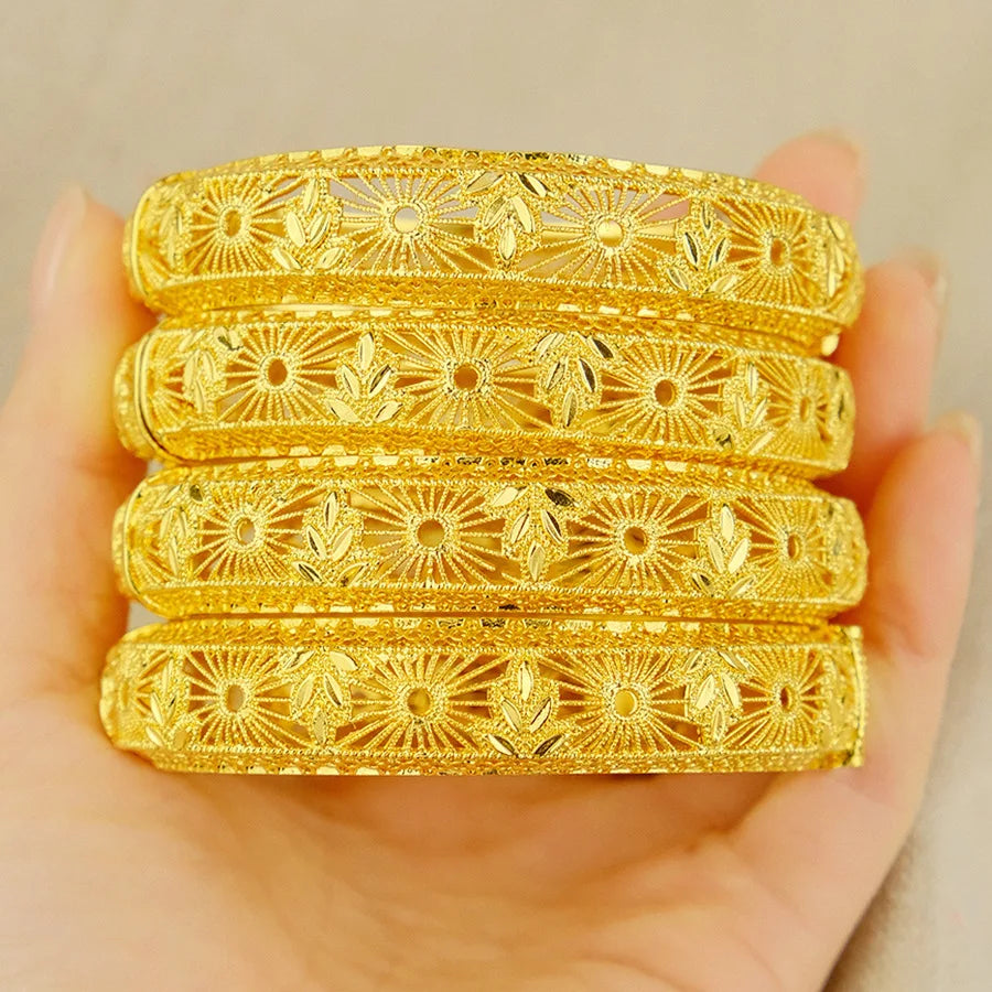 Set of gold bangles with intricate designs on a beige background