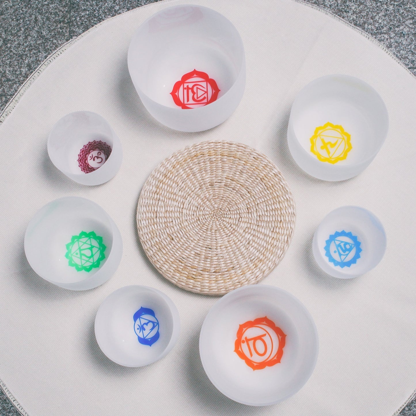 Set of small white bowls with colorful symbols on a woven mat - Seven Chakra Crystal Buddha Sound Bowl multicolor rainbow chakra Crystal Buddha sound bath