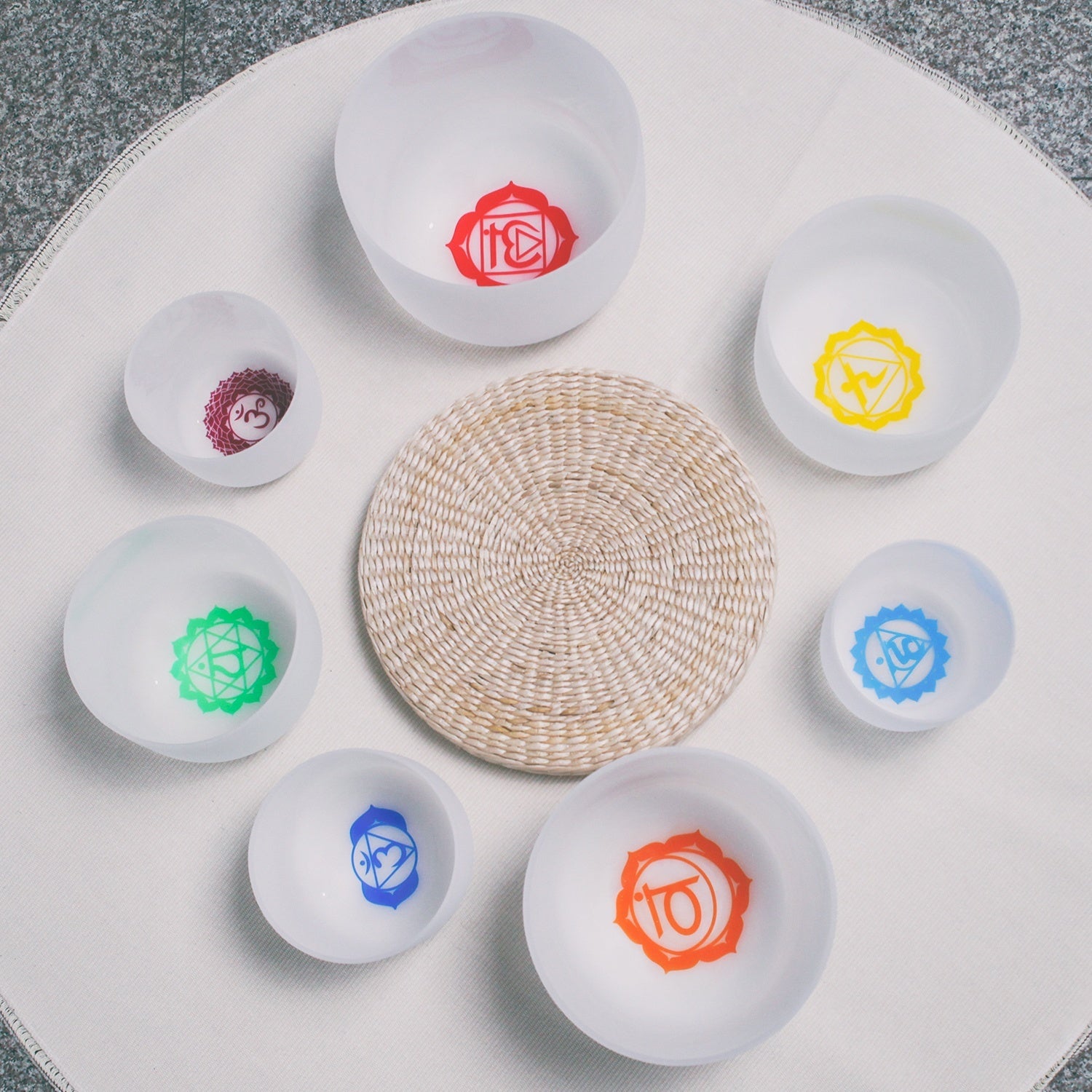 Set of small white bowls with colorful symbols on a woven mat - Seven Chakra Crystal Buddha Sound Bowl multicolor rainbow chakra Crystal Buddha sound bath