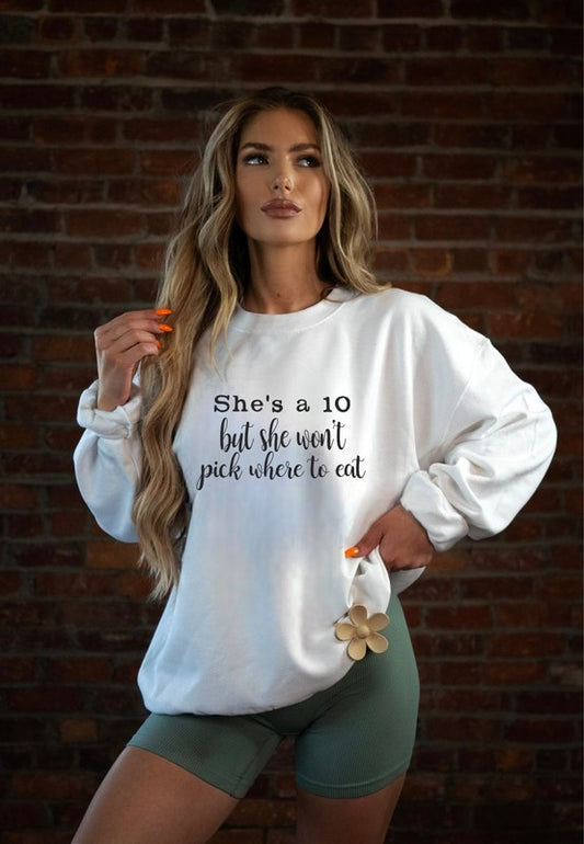 Woman wearing a white sweatshirt with text against a brick wall