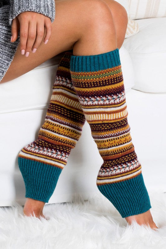 Woman wearing multicolor Fair Isle knit leg warmers featuring a classic Nordic-inspired pattern in red, gray, navy, and cream tones. These soft acrylic leg warmers showcase a thick ribbed cuff and cozy textured knit construction, providing warmth and comfort for cold-weather styling. Perfect for pairing with boots, leggings, jeans, tights, and winter outfits, these fashionable leg warmers add a rustic cabin-chic touch to everyday wear. Ideal for fall and winter fashion, holiday outfits, ski lodge getaways, 