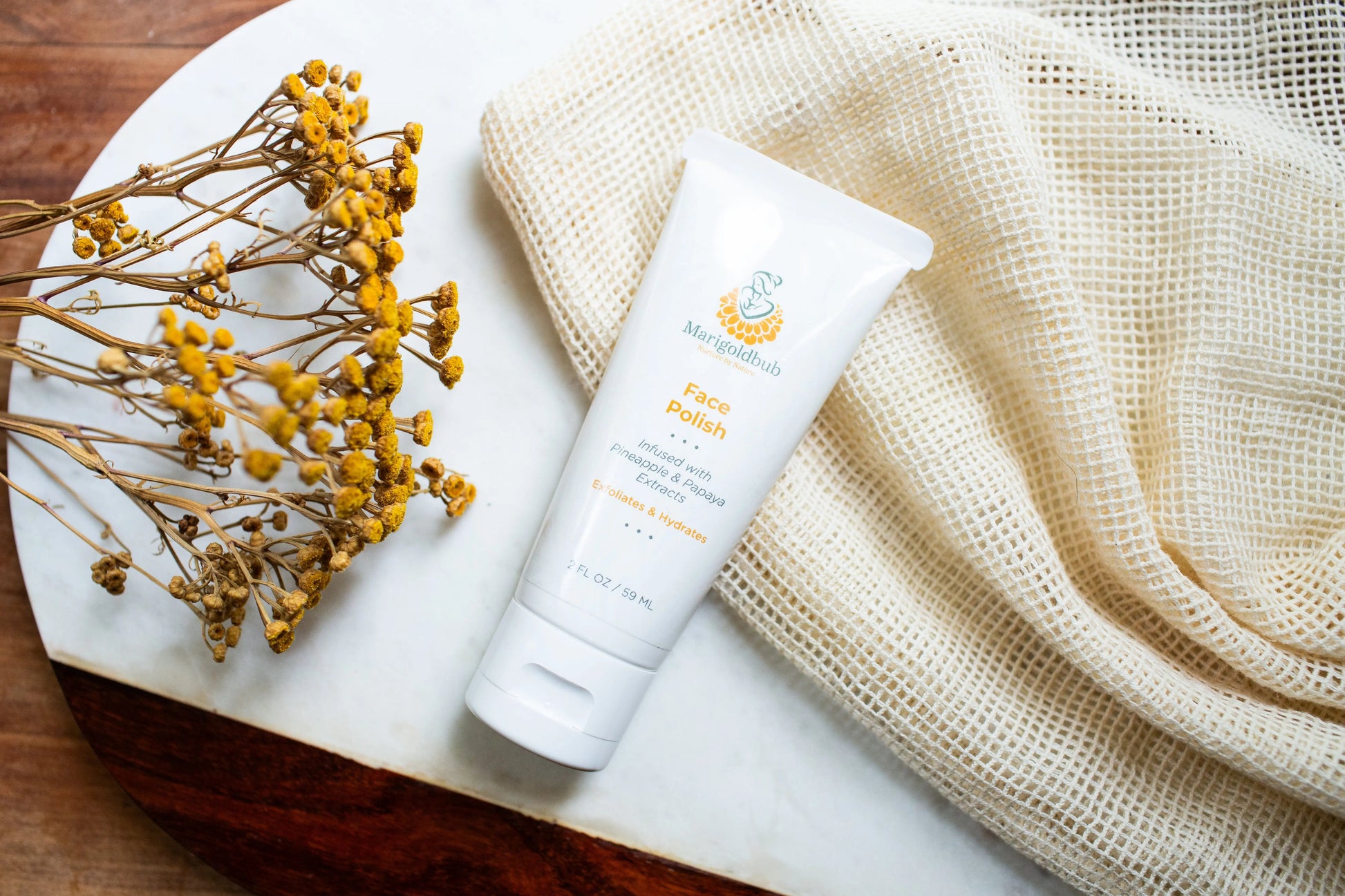 Luxury flat lay of Marigoldbub Face Polish infused with Ayurvedic botanicals on a white marble tray with dried flowers and natural linen cloth, clean beauty facial exfoliator, botanical skincare, vegan, cruelty-free, natural skincare, spa-inspired self-care, radiant glowing skin.