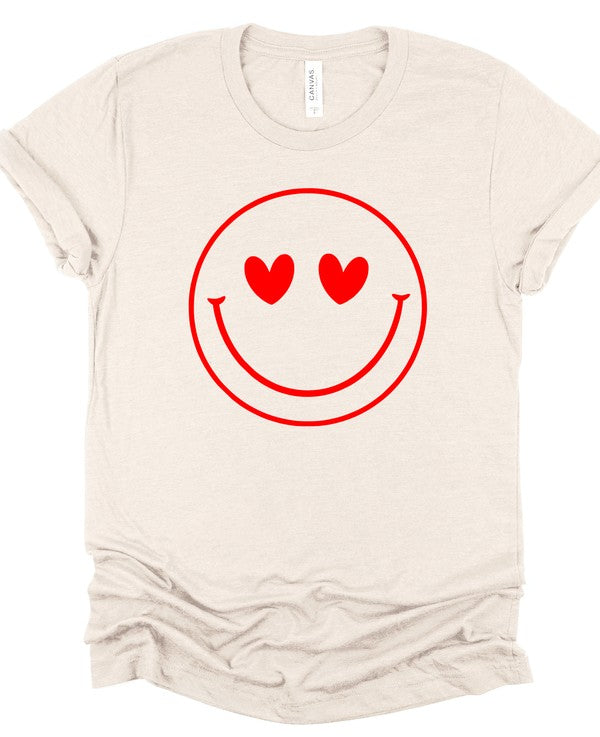 Cream Bella+Canvas unisex T-shirt featuring a bold red smiley face graphic with heart-shaped eyes, displayed with rolled sleeves on a clean white background for a fun, playful casual style.
