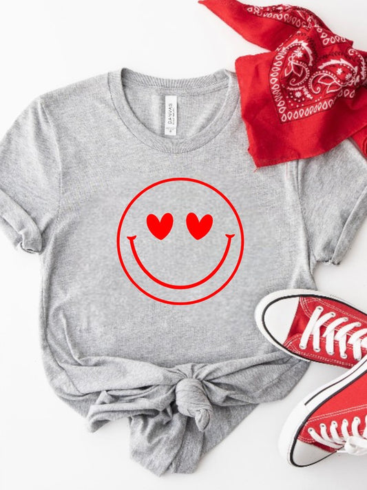 Gray t-shirt with red smiley face design featuring hearts, paired with a red bandana and sneakers on a white background. Smiley Face Heart Eyes Graphic Bella+Canvas Unisex T-Shirt – Cute Emoji Soft Premium Tee for Women & Men | Cozy Casual Graphic Shirt Gift