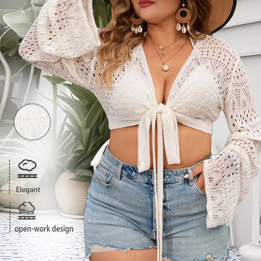 Woman wearing a white lace top and denim shorts with a plant and vase in the background