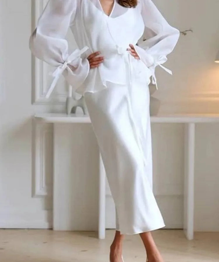 Elegant white satin two-piece skirt set with puff long sleeves, tie-cuff details, patchwork design, and matching midi skirt for women's casual, evening, wedding guest, and special occasion fashion.