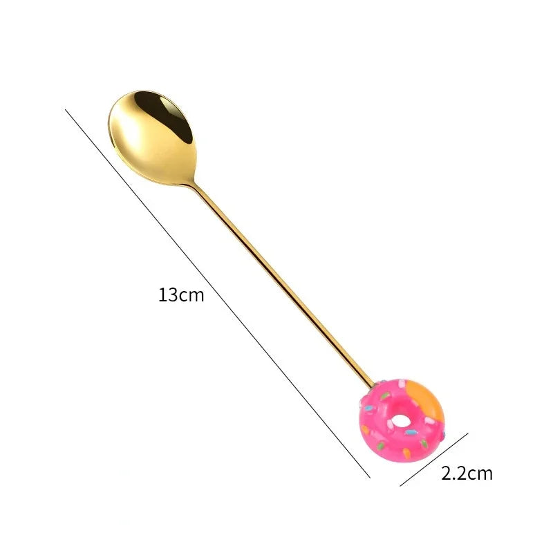 Gold spoon with a pink donut-shaped handle on a white background