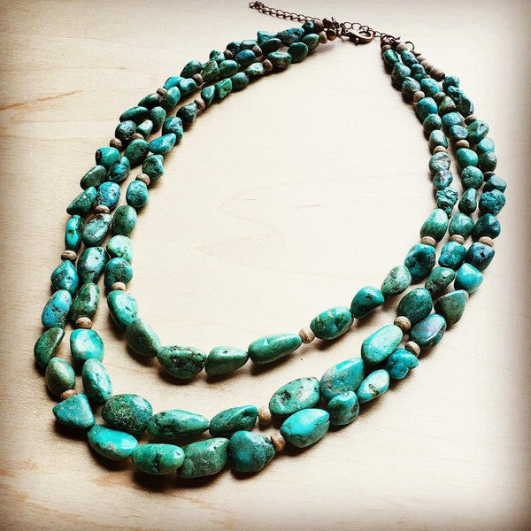 TRIPLE STRAND • TURQUOISE + WOOD • STATEMENT COLLAR
Triple Strand Turquoise &amp; Wood Collar Necklace

Make a bold statement with a triple strand collar necklace where rich turquoise stones meet warm wood accents for an effortlessly chic, collected look. Every piece is made with natural materials, so no two necklaces ever match—your collar will have its own mix of gemstone sizes and signature patterning. Wear it solo as your centerpiece or layer it with longer chains for a styled, elevated stack.