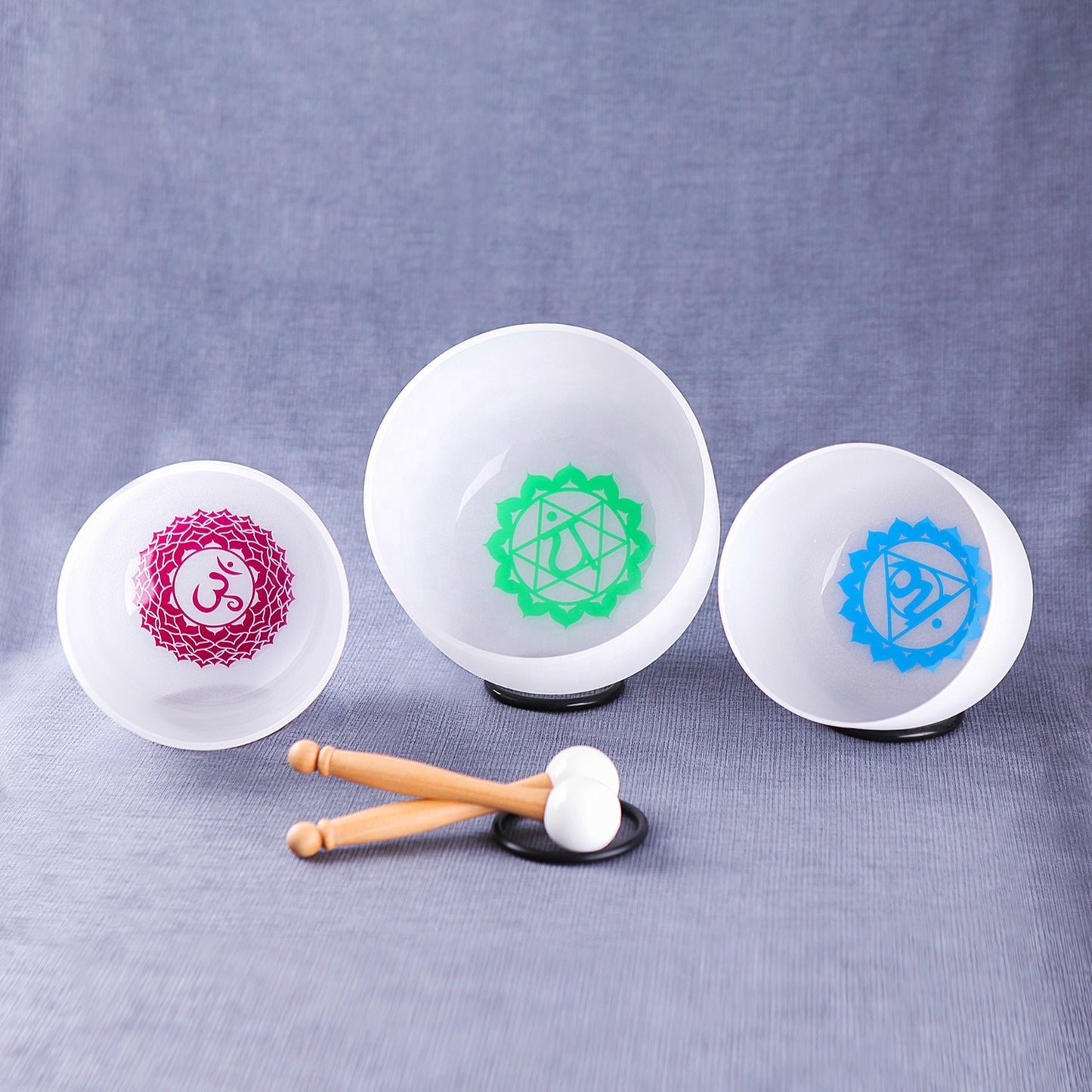 Three white stress balls with different symbols and a hammer on a gray background Set of small white bowls with colorful symbols on a woven mat - Seven Chakra Crystal Buddha Sound Bowl multicolor rainbow chakra Crystal Buddha sound bath