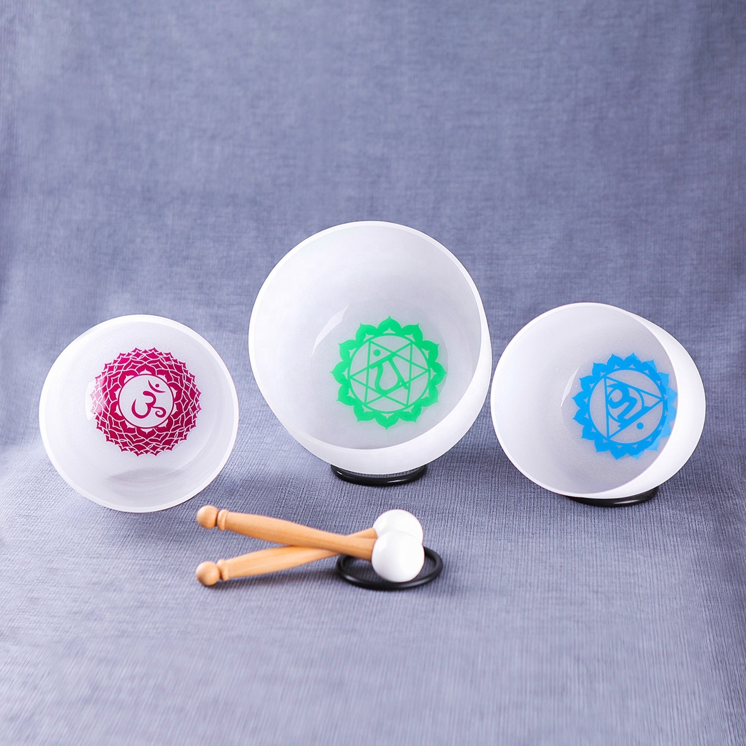 Three white stress balls with different symbols and a hammer on a gray background Set of small white bowls with colorful symbols on a woven mat - Seven Chakra Crystal Buddha Sound Bowl multicolor rainbow chakra Crystal Buddha sound bath